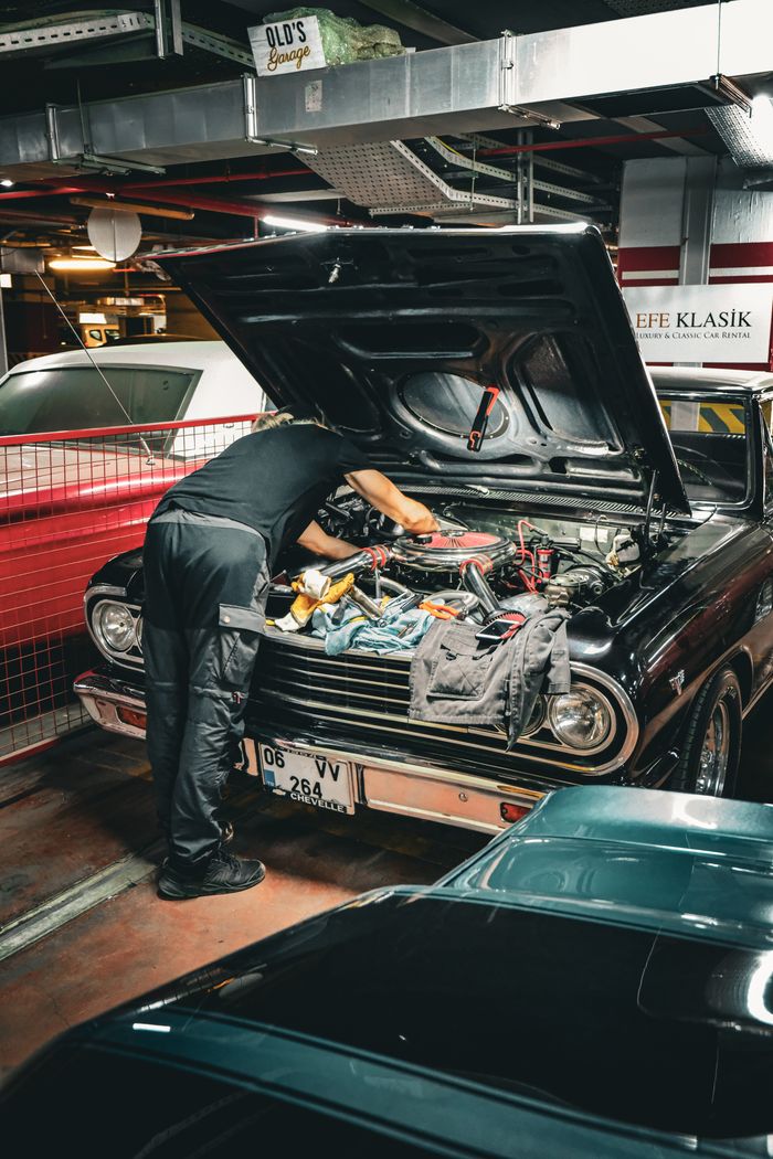 services-02 Mechanic repairing classic car engine in an Ankara garage, capturing vintage automotive repair scene.