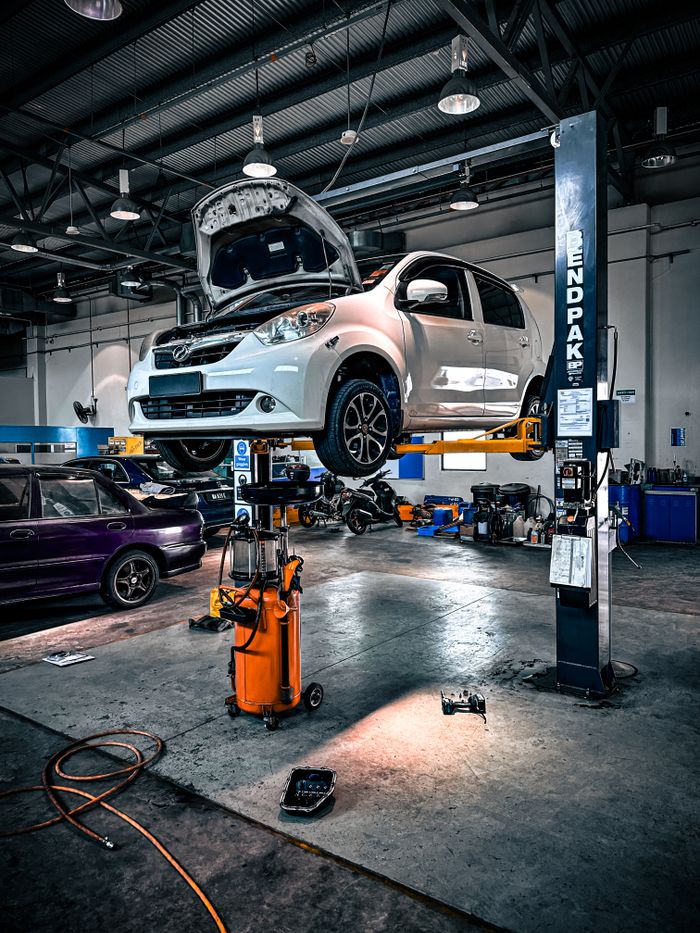 services-02 A car is lifted on a hydraulic lift in a well-equipped auto repair shop.