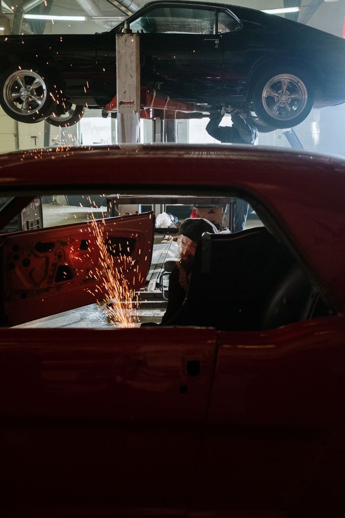 Mastering the First Impression: Your intriguing post title goes here A mechanic welding inside a car workshop with a vehicle on a lift above.