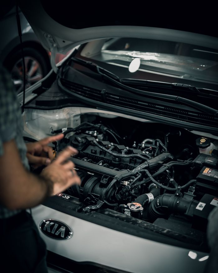 about-us Mechanic inspecting a car engine for maintenance work in a garage.